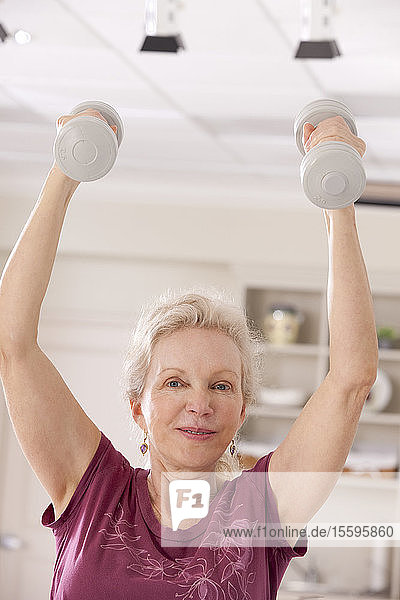 Porträt einer älteren Frau  die mit Hanteln in einem Fitnessstudio trainiert