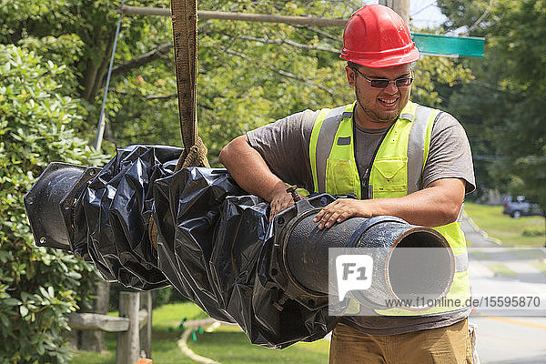 Construction worker guiding water main into place