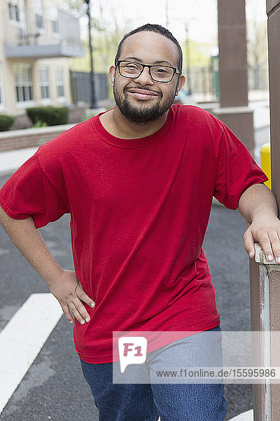 Porträt eines glücklichen afroamerikanischen Mannes mit Down-Syndrom  der im Freien steht