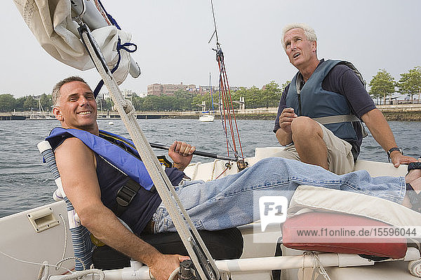 Portrait of a mid adult man reclining in a boat for adaptive sailing with a middle-aged man sitting beside him
