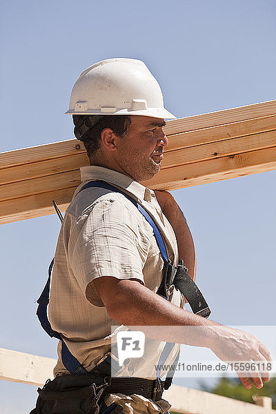 Zimmermann trägt Wandständer auf einer Baustelle