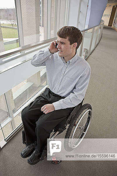 Businessman with spinal cord injury in a wheelchair and talking on a mobile phone