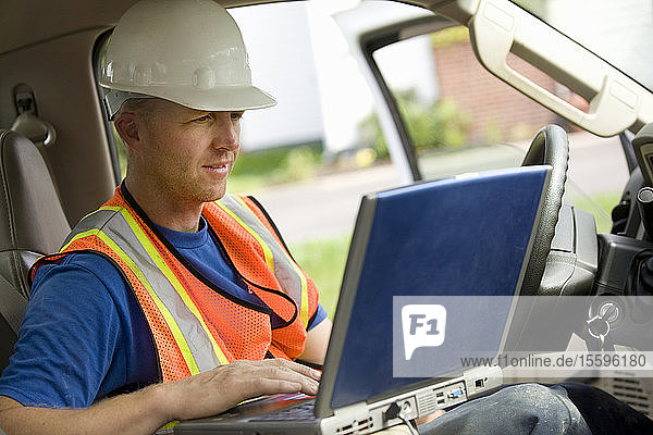 Bauarbeiter benutzt Laptop im Lkw