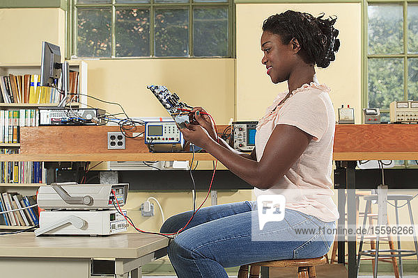Ingenieurstudent bei einer Messung auf einer Mikrocontroller-Platine in einem Elektronikunterrichtsraum