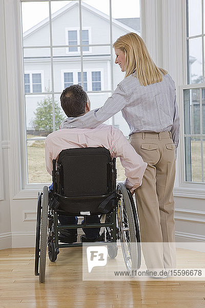 Man sitting in a wheelchair with a woman standing beside him