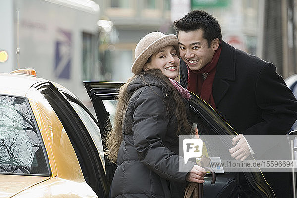 Portrait of a young couple smiling together near a taxi