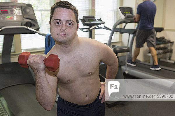 Mann mit Down-Syndrom trainiert in einer Turnhalle mit Hantel
