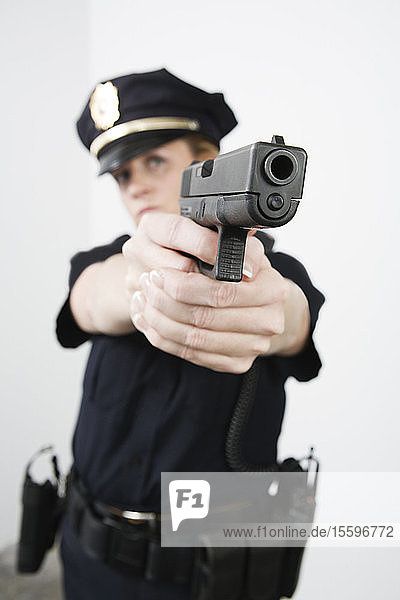 Blick auf eine Polizistin  die mit einer Pistole zielt.