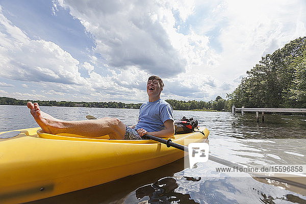 Happy young man with Down Syndrome rowing a kayak in a lake