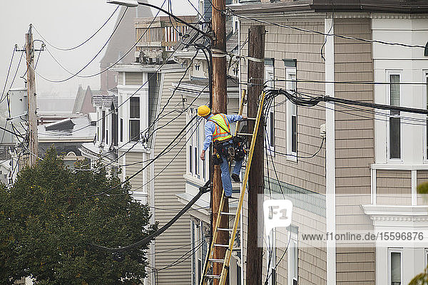 Cable lineman assessing cable distribution wiring on poles in the city