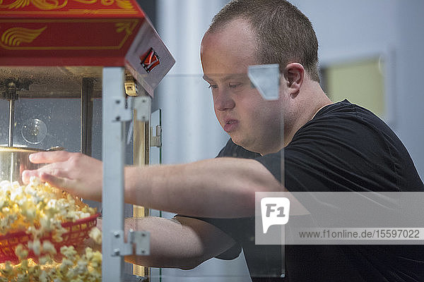Kellner mit Down-Syndrom holt Popcorn in einem Restaurant