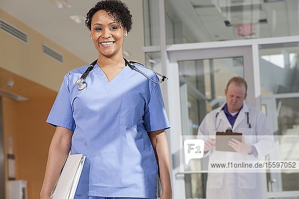 Porträt einer lächelnden Krankenschwester  hinter der ein männlicher Arzt steht