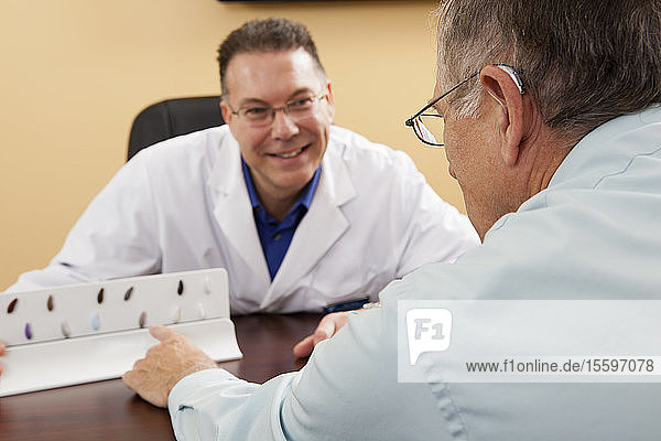 Patient choosing hearing aid color with an audiologist