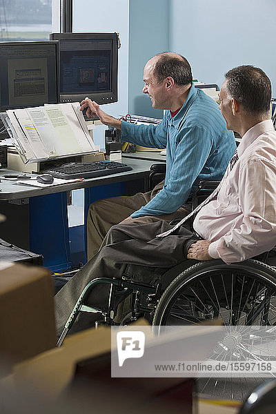 Zwei Geschäftsleute in einem Büro  einer mit Friedreich-Ataxie  der andere mit einer Rückenmarksverletzung