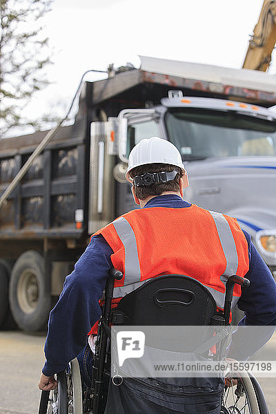Construction engineer with spinal cord injury watching dump truck operations