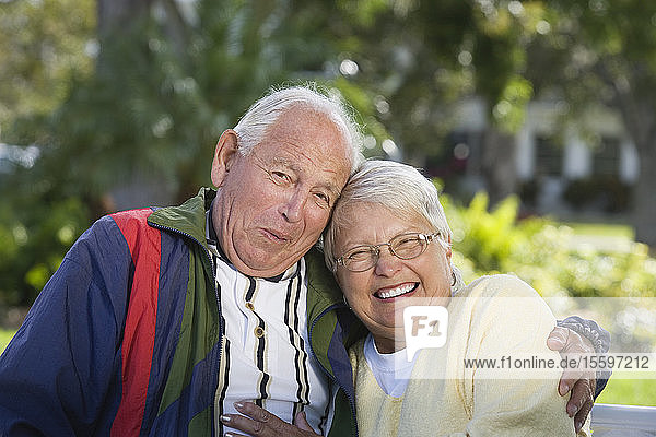 Portrait of a senior couple in a park smiling.