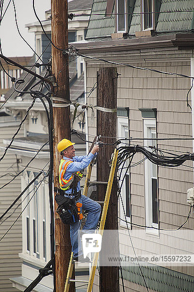 Kabelmonteur bei der Installation eines Filters an den Strommasten der Stadt