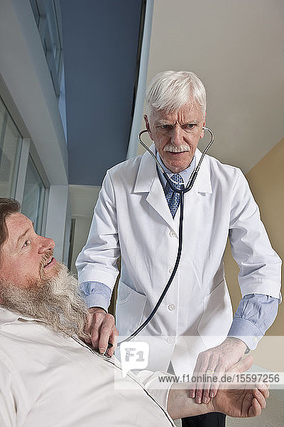 Arzt  der einen Patienten mit einem Stethoskop untersucht  der Patient ist bipolar