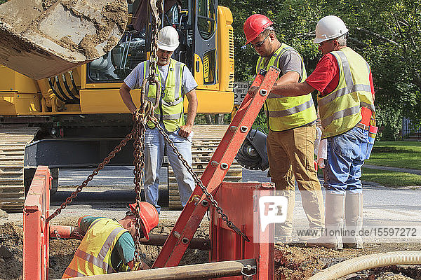 Bauarbeiter bereiten sich darauf vor  mit einer Leiter in ein Loch zu steigen