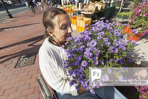 Woman in wheelchair with spinal cord injury shopping at outdoor market for flowers
