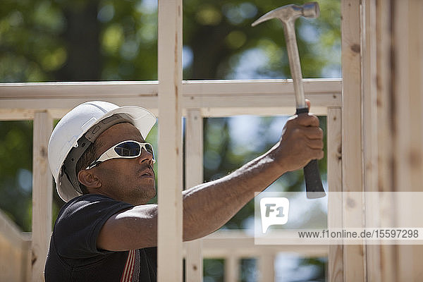 Zimmermann nagelt auf einer Baustelle ein Holzgerüst an