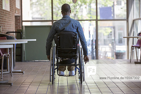 Man who had Spinal Meningitis in a wheelchair heading for a stair lift in an office