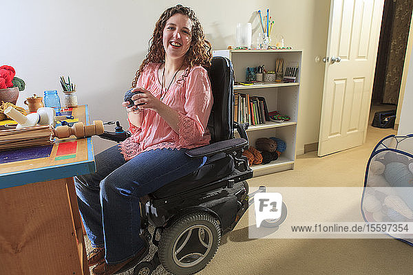 Frau mit Muskeldystrophie arbeitet in ihrem Rollstuhl mit ihrem Garnwickler
