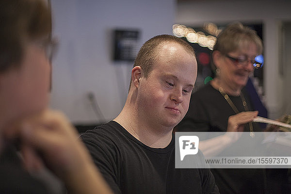 Waiter with Down Syndrome working in a restaurant with other female colleagues
