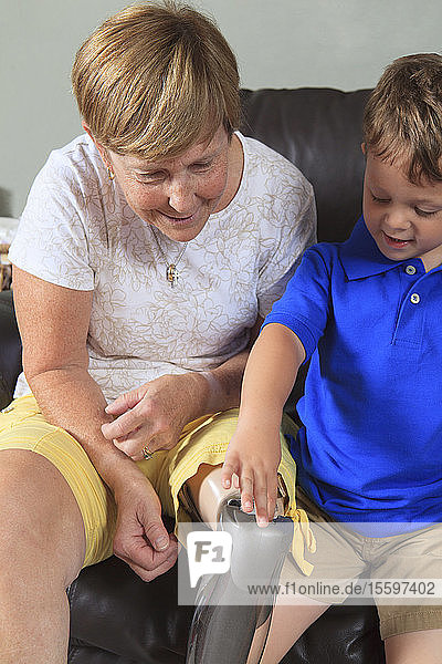 Großmutter mit ihrem Enkel  der mit ihrer Beinprothese spielen darf