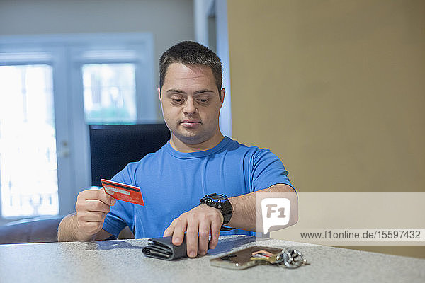 Mann mit Down-Syndrom hält eine Kreditkarte