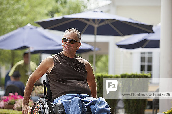 Man with spinal cord injury in a wheelchair sitting at a cafe
