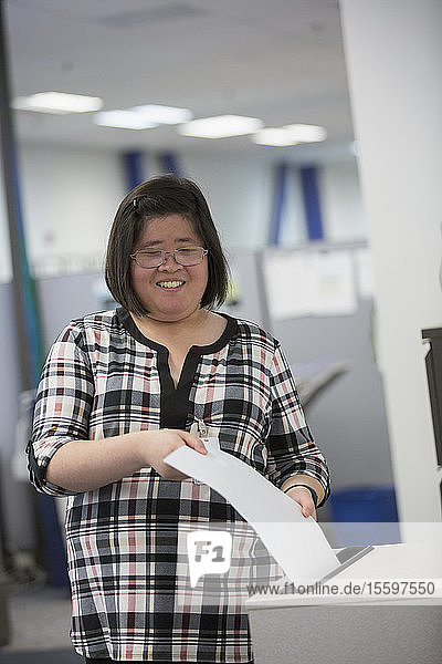 Asiatische Frau mit einer Lernbehinderung arbeitet in einem Büro
