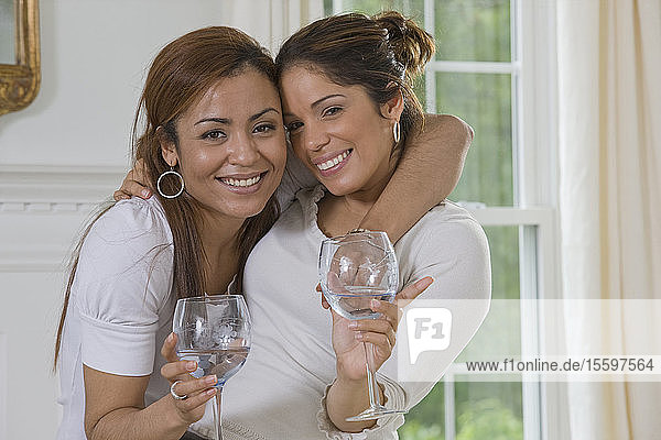 Zwei hispanische Frauen halten Weingläser