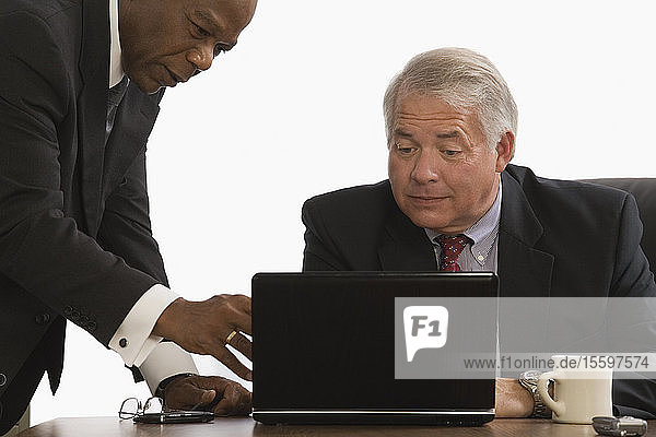Zwei Geschäftsleute schauen auf einen Laptop in einem Büro