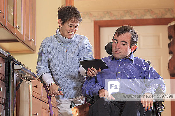 Ehepaar mit Cerebralparese schaut auf ihr Tablet