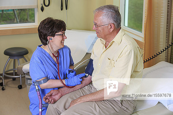 Krankenschwester mit Zerebralparese misst den Blutdruck eines Patienten in einer Klinik