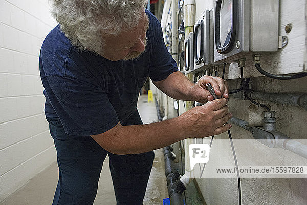 Ingenieur  der das Sondenkabel des elektrochemischen O2-Sensors mit dem Messgerät in einer Wasseraufbereitungsanlage verbindet