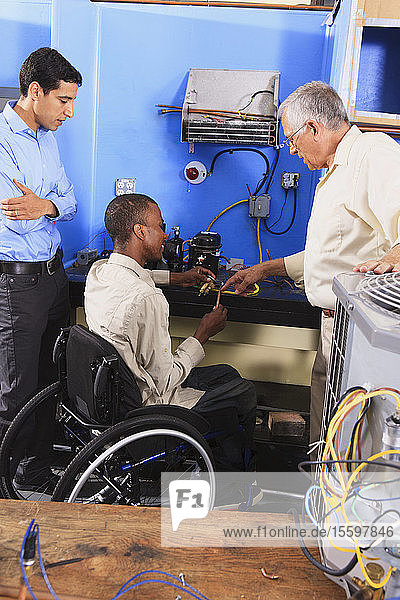 Instructor discussing condenser coil on refrigeration unit with student in wheelchair