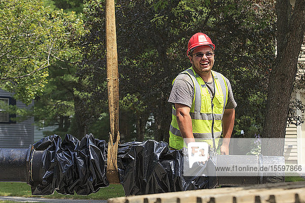 Construction worker guiding water main into place