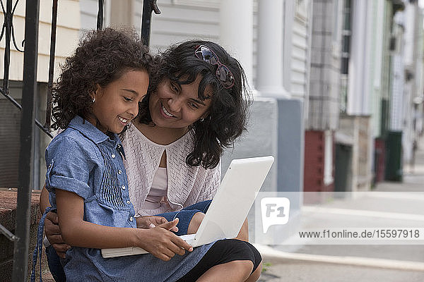 Hispanisches Mädchen benutzt mit ihrer Mutter einen Laptop