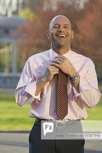 Portrait of an Hispanic businessman adjusting his tie