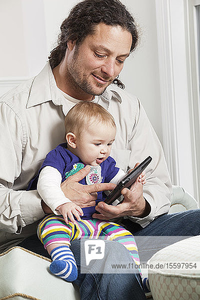 Father and baby looking at electronic tablet at home