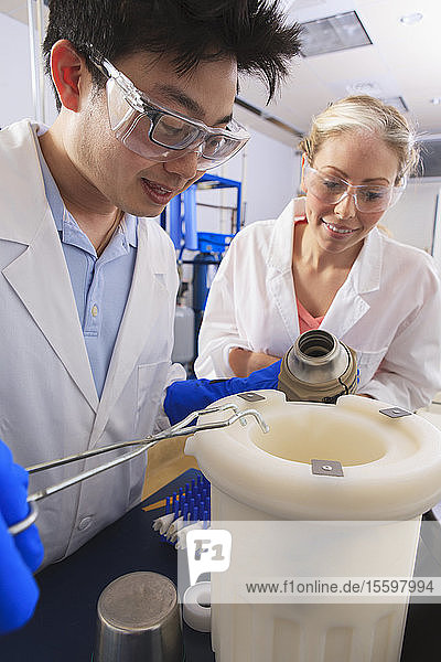 Studenten der Ingenieurwissenschaften verwenden eine Pinzette  während sie einen Dewar-Kolben mit flüssigem Stickstoff in einem Wasseraufbereitungsraum in einem Labor halten