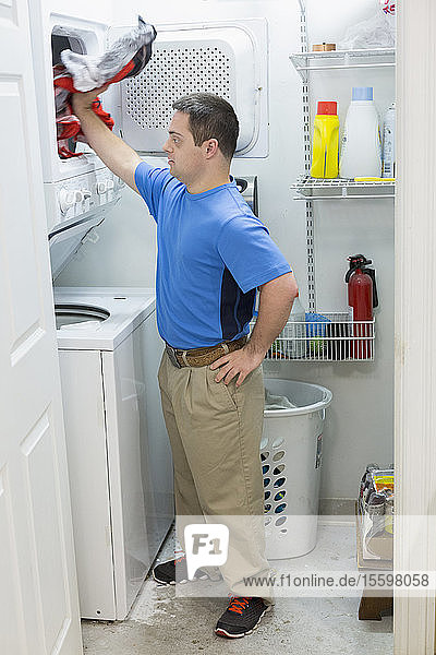 Mann mit Down-Syndrom steht in der Waschküche