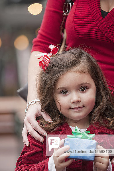 Porträt eines Mädchens  das mit seiner Mutter steht und ein Weihnachtsgeschenk hält