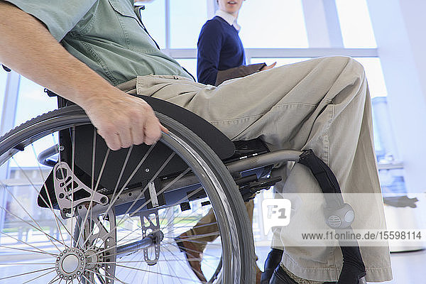 Mann im Rollstuhl mit Muskeldystrophie  der einen Korridor benutzt