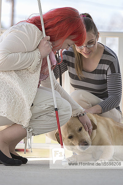 Zwei Frauen mit Sehbehinderungen  eine mit einem Diensthund und eine mit einem Blindenstock