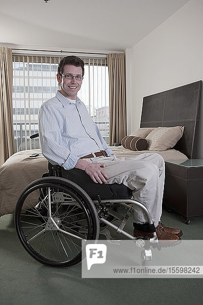 Mann im Rollstuhl mit einer Rückenmarksverletzung im Schlafzimmer