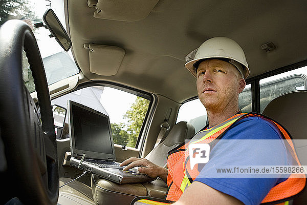 Bauarbeiter benutzt Laptop im Lkw
