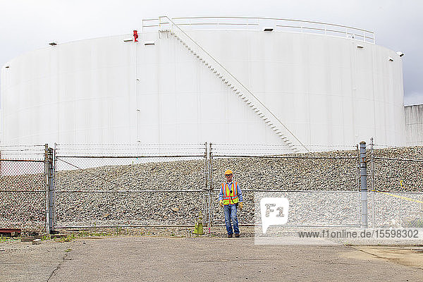 Engineer standing in front of fuel storage tank depot